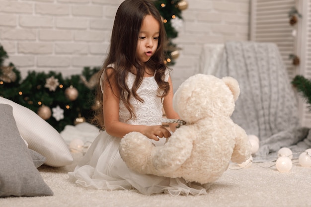 Pretty little girl with a teddy bear on Christmas