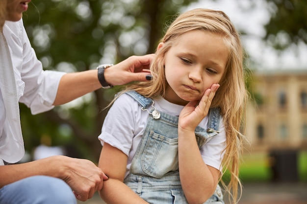 pretty lovable little girl propping up her face at summer green park