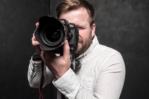 pretty man  photographer in white shirt shoots in the studio on DSLR camera which stands on tripod