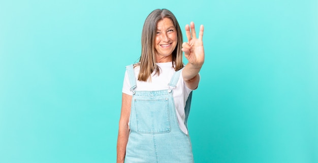 Pretty middle age woman smiling and looking friendly, showing number three