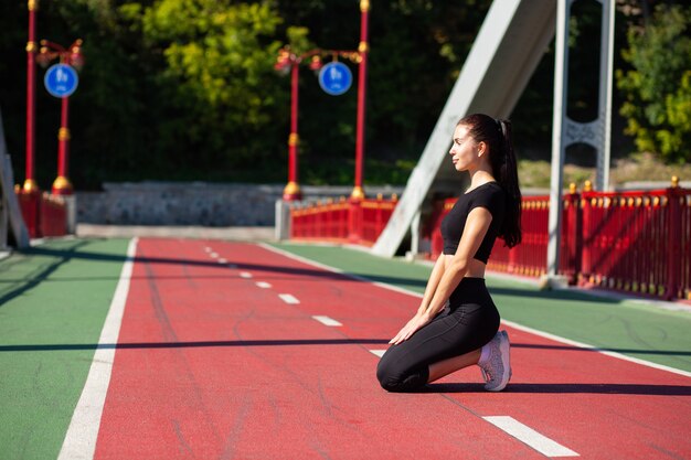 Pretty model athlete in sport apparel doing stretching at the bridge. Space for text