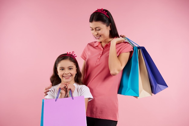 Pretty mom and daughter in casual clothes with paper bags.