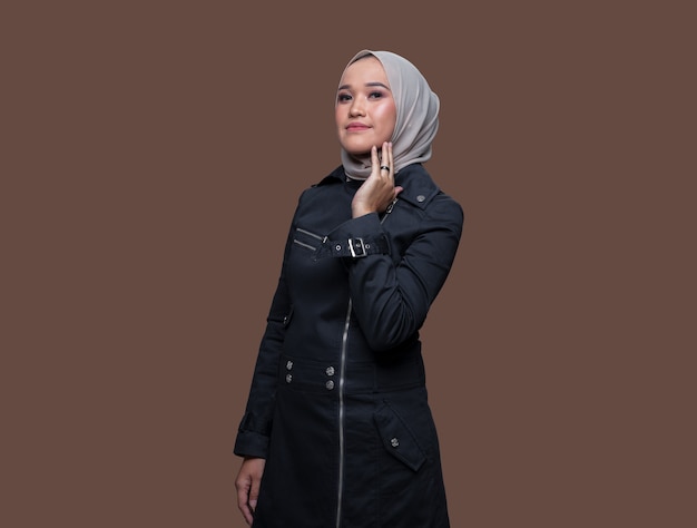 Pretty Muslim woman wearing hijab posing on plain background