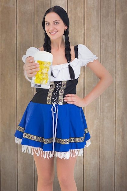 Pretty oktoberfest girl holding beer tankard against wooden surface with planks