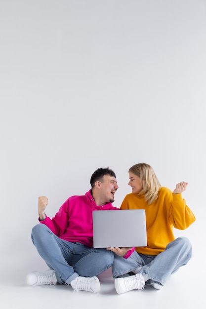 Pretty portrait of couple with laptop sitting down gray background