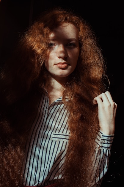 Pretty red haired model with freckles and long hair. Woman with shadow on her face