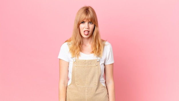 Photo pretty red head woman feeling disgusted and irritated and tongue out