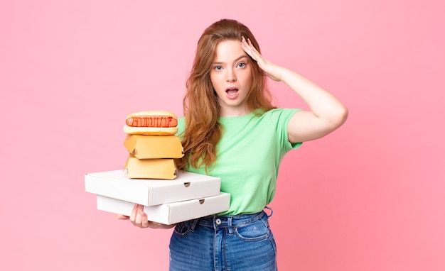 Pretty red head woman holding take away fast food boxes