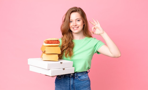 Pretty red head woman holding take away fast food boxes