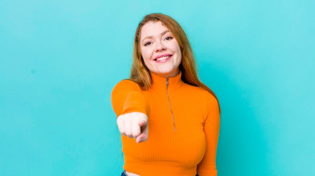 Photo pretty red head woman pointing at camera with a satisfied confident friendly smile choosing you