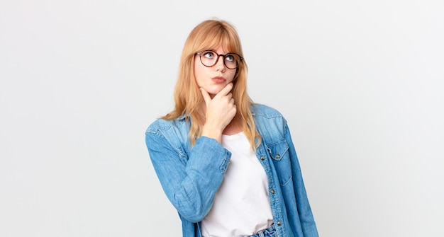 pretty red head woman thinking, feeling doubtful and confused