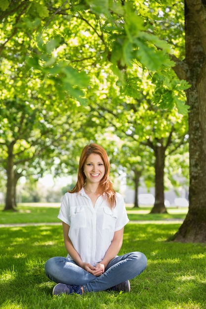 Pretty redhead smiling at camera in the park