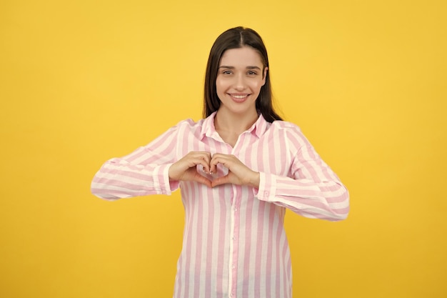 Pretty romantic young woman making a heart gesture showing love and affection grateful gesture with a happy tender smile Girl feelings love Lovely woman with heart sign symbol