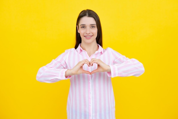 Pretty romantic young woman making a heart gesture showing love and affection grateful gesture with a happy tender smile Girl feelings love Lovely woman with heart sign symbol