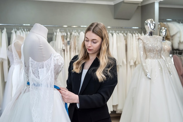 A pretty sales consultant measures a wedding dress for a client and shows impeccable quality