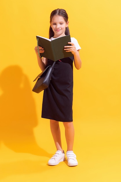 Pretty schoolgirl kid wearing modern school uniform isolated on yellow background concept of