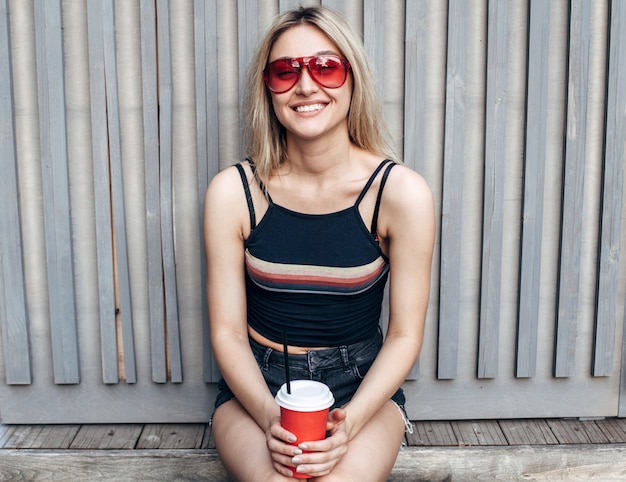 Pretty sensual stylish blonde woman are posing near wood wall in summer on the street urban style