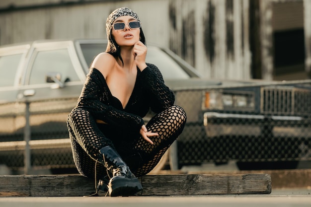 Photo pretty sexy fashion sensual woman posing on garage wall hipster young woman in hipster style outfit stylish fashionable girl in black clothes beautiful sexy woman sitting near retro car