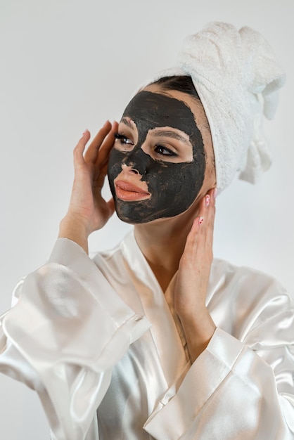 Pretty sexy woman applying clay black mask on white background