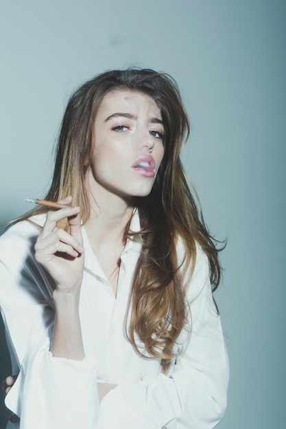 Pretty sexy woman or girl with long hair smoking cigarette