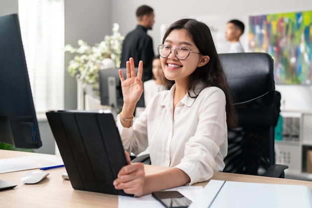 A pretty smiling korean asian woman sits in the office wearing a smart white shirt a businesswoman