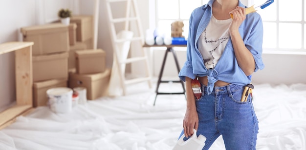 Pretty smilling woman painting interior wall of home with paint roller