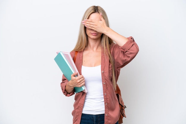 Pretty student blonde woman isolated on white background covering eyes by hands Do not want to see something