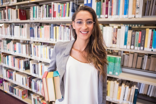 Pretty student holding books in library