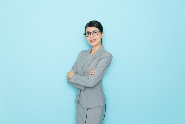 pretty sweet woman right agent worker looking at camera smiling and standing in blue wall background office with empty area.