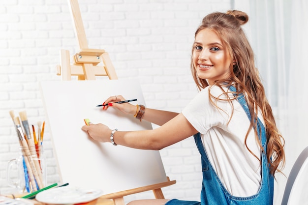 Pretty talented female painter painting on easel