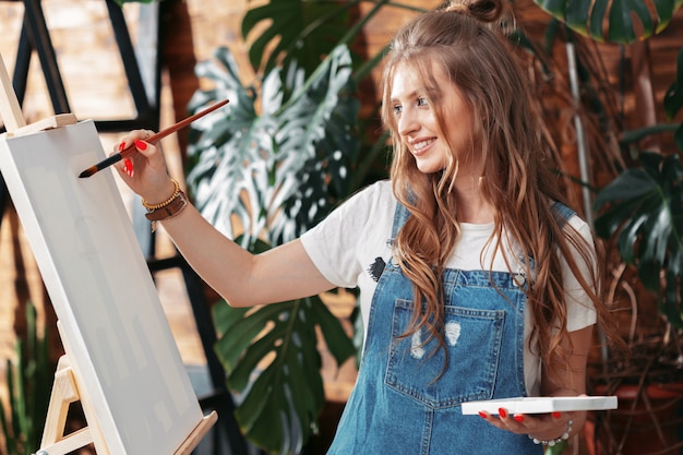 Pretty talented female painter painting on easel