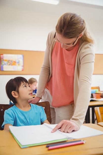 Pretty teacher helping pupil in classroom