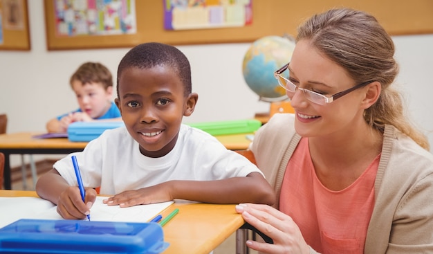 Pretty teacher helping pupil in classroom