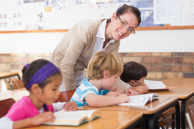 Pretty teacher helping pupil in classroom