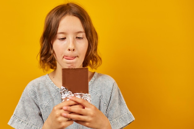 Pretty teen girl with a chocolate bar isolated