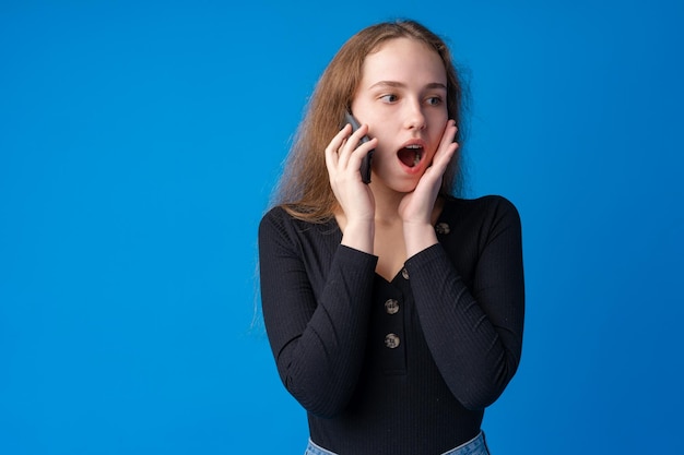 Pretty teenage girl talking on the mobile phone against blue background