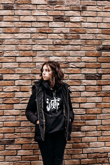 Pretty teenager girl in front of bricks wall Black wearing teen looking aside