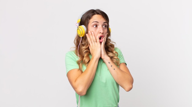 Pretty thin woman feeling happy, excited and surprised listening music with headphones