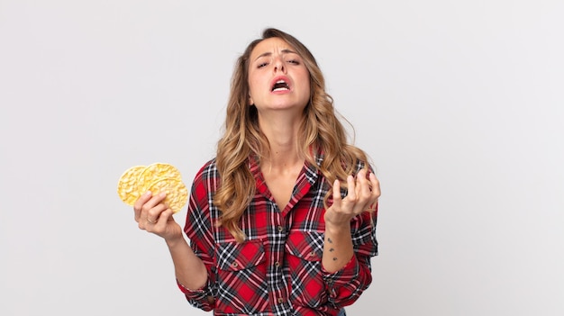 Pretty thin woman looking desperate frustrated and stressed and holding a diet rice cakes