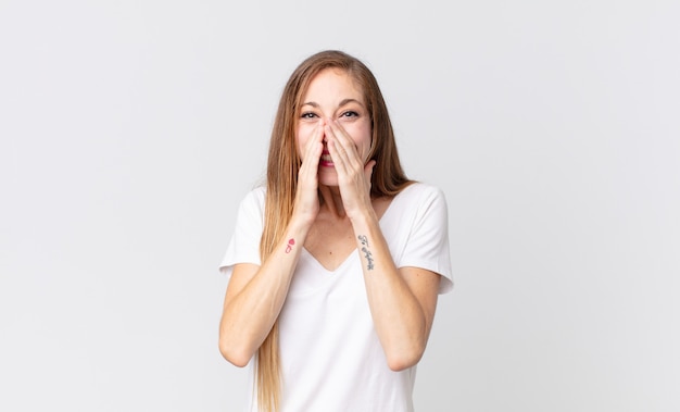 pretty thin woman looking happy, cheerful, lucky and surprised covering mouth with both hands