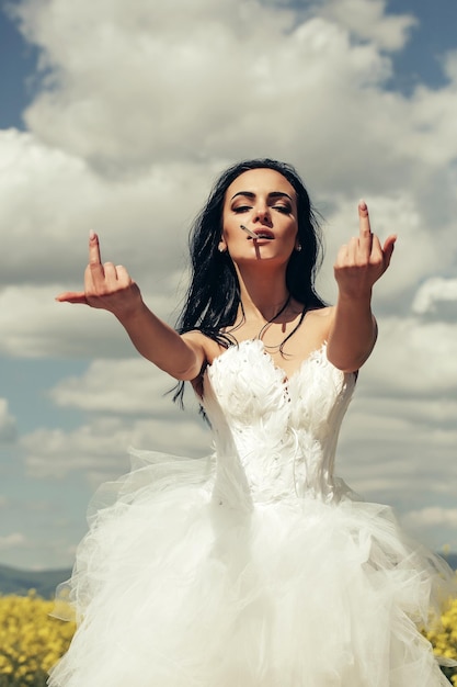 Pretty wedding girl on blue sky with middle finger