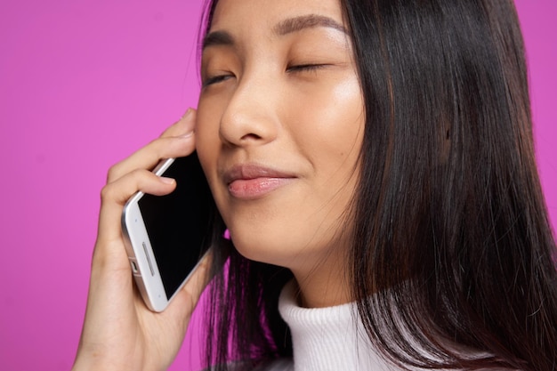 Pretty woman asian appearance telephone communication technology closeup pink background