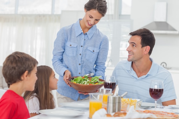 Pretty woman bringing a salad to her family