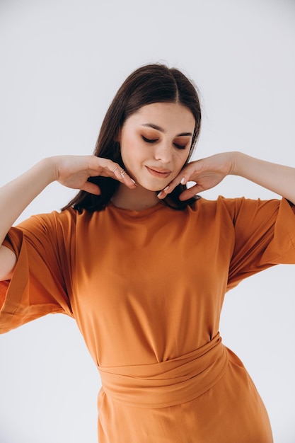 pretty woman on a cyclorama in a photo studio dressed in a stylish mustardcolored oversize dress