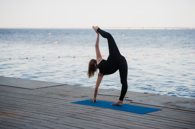 pretty woman doing yoga at the lake