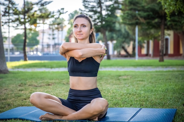 Pretty woman doing yoga in morning park Healthy lifestyle outdoor conception Sport Woman nature portrait doing exercises Healthy lifestyle