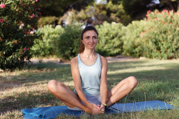 Pretty woman doing yoga in morning park Healthy lifestyle outdoor conception Sport Woman nature portrait doing exercises Healthy lifestyle