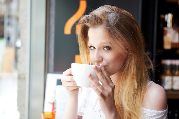 Pretty woman drinks a cup of coffee