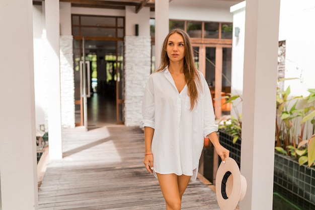 Pretty woman enjoing tropical vacations in Thailand, wearing white blouse at luxury villa.