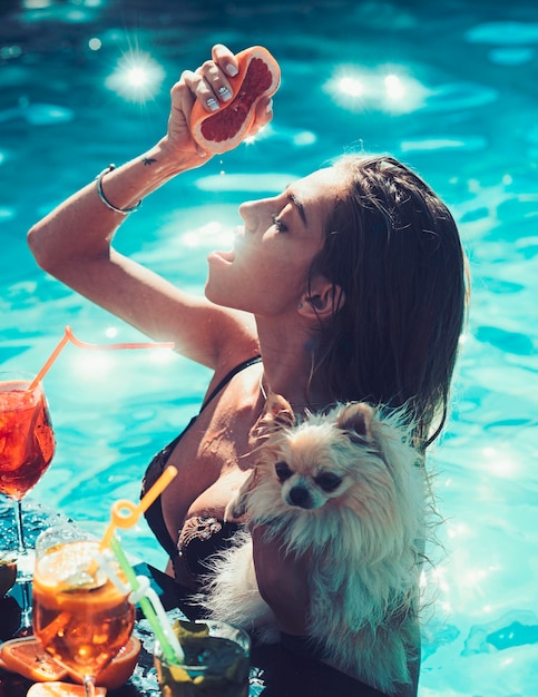 Pretty woman enjoying a fresh juice and cocktail in a swimming pool